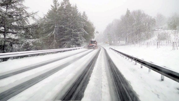 Neuschnee im Erzgebirge; Verschneite Straße, ein Räumfahrzeug schiebt Schnee.