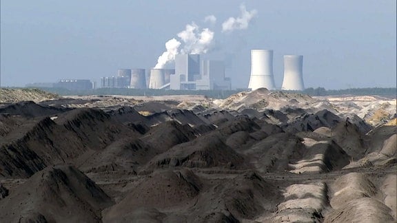 Braunkohlekraftwerk am Horizont, davor Tagebaulandschaft.