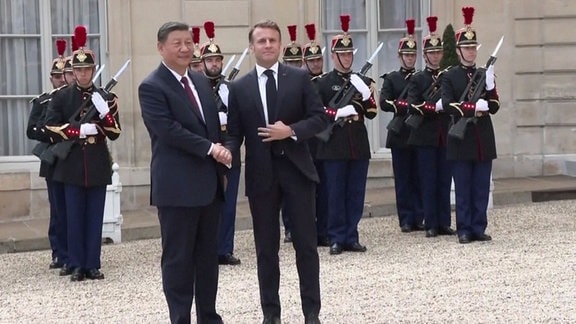 Xi XingPi wird von Emmanuel Macron begrüßt.