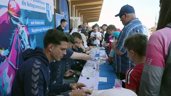 Spieler des 1. FC Magdeburg schreiben Autogramme.
