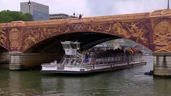 Olympiaeröffnung - Schiff mit Athlethen fährt unter einer Brücke hindurch.