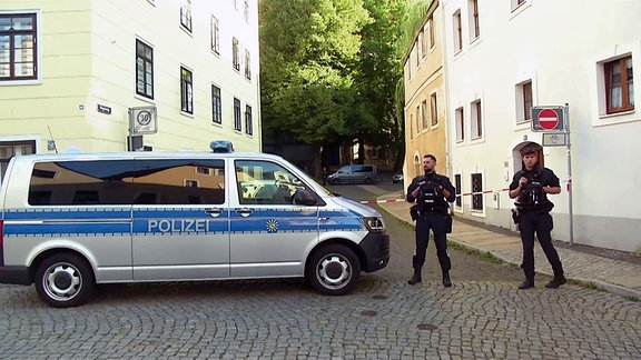 Ein Polizeiauto und zwei Polizisten vor einer Schule