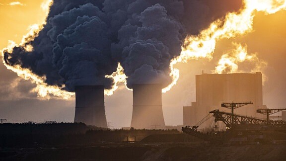 Das Kohlekraftwerk Schwarze Pumpe zeichnet sich vor der aufgehenden Sonne ab.