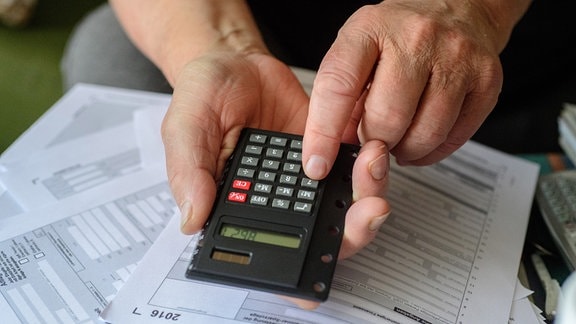 Ein Rentner tippt angesichts der fälligen Steuererklärung in seinen Taschenrechner. 