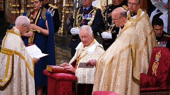 König Charles III hält in Westminster Abbey seine Hände auf der Bibel.