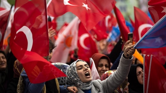 Anhänger des türkischen Präsidenten Erdogan schwenken türkische Nationalfahnen bei einer Wahlkampfveranstaltung.