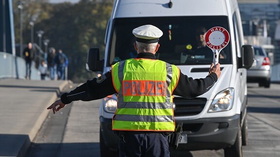 Ein Beamter der Bundespolizei stoppt einen Fahrer eines Kleintransporters