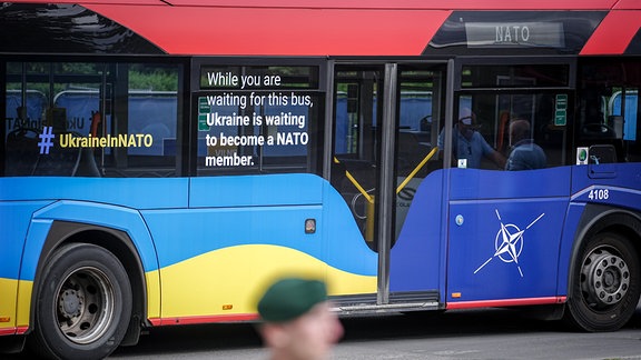„While you are waiting for this bus, Ukraine is waiting to become a Nato member.“ steht auf einem Shuttlebus beim Nato-Gipfel.