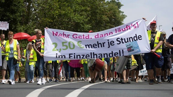Streikende gehen während eines Warnstreiks mit einem Banner «Mehr Geld, dann läufts! 2,50 € mehr je Stunde im Einzelhandel!» an dem Ikea-Verwaltungssitz und der Filiale entlang