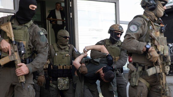 Angehörige der Spezialeinheit der kosovarischen Polizei eskortieren einen der festgenommenen serbischen Staatsbürger aus dem Gerichtssaal.