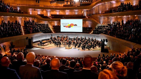 Menschen besuchen einen Festakt anlässlich der Feierlichkeiten zur deutschen Wiedervereinigung in der Elbphilharmonie.