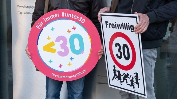Vor dem Verwaltungsgericht werden zwei Schilder mit der Aufschrift «Für immer #unter30» und «Freiwillig 30» gezeigt.