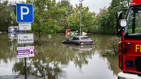 Ein Auto steht auf einem überfluteten Parkplatz.