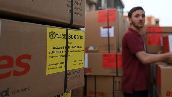 Mann sortiert Kisten mit Hilfsgütern