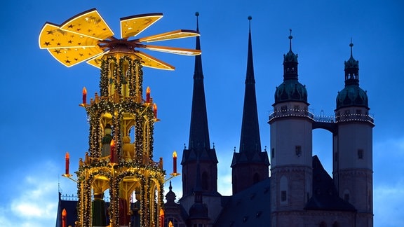 Die große Weihnachtspyramide vor der Silhouette der Marktkirche. Die Stadt Halle hat den Weihnachtsmarkt in diesem Jahr trotz steigender Coronazahlen geöffnet.
