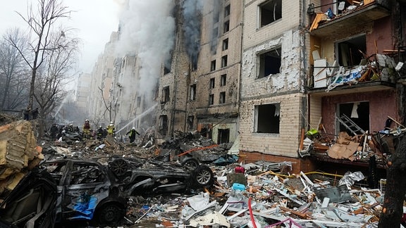 Beschädigte Autos liegen neben einem zerstörten Wohnhaus nach einem russischen Angriff.