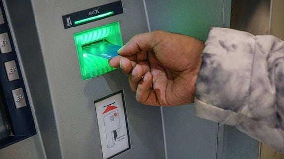 Ein Mann mit einer SocialCard fuer Asylsuchende an einem Geldautomaten