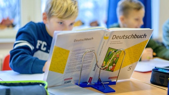 Ein Junge schaut in ein Deutschbuch