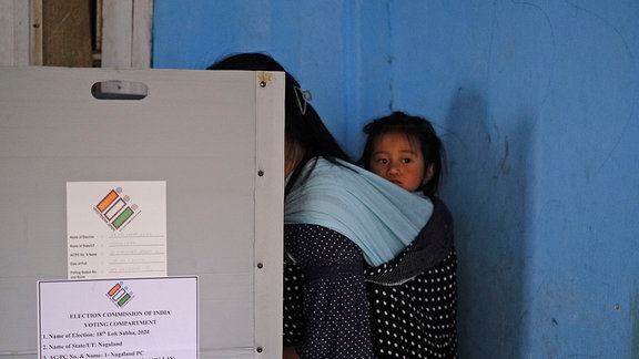 Mit ihrem Kleinkind auf dem Rücken gibt eine Frau ihre Stimme beim ersten Wahlgang der indischen Parlamentswahl im Dorf Chedema im nordöstlichen indischen Bundesstaat Nagaland ab. 