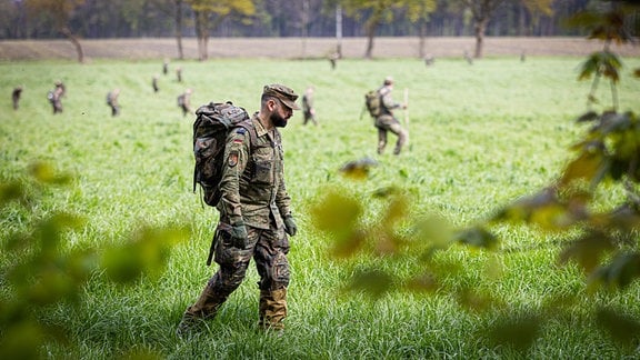 Soldaten der Bundeswehr suchen ein Feld ab.