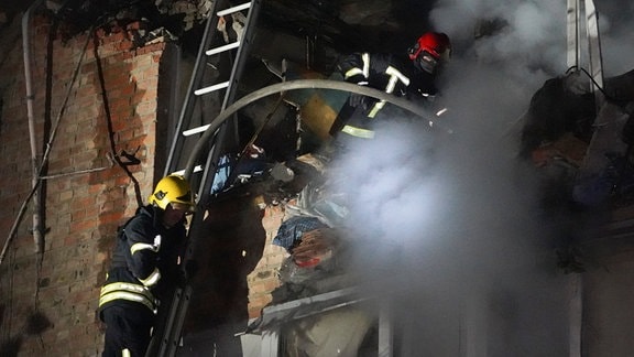 Feuerwehrleute löschen ein Feuer in einem Wohnhaus, das bei einem russischen Raketenangriff beschädigt wurde. 