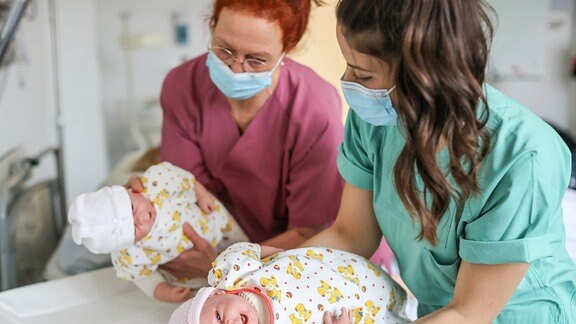 Die Studentin Lea (r) übt unter Anleitung von Bianca Hünlich, Lehrkraft für Hebammenkunde, das Aufnehmen eines Neugeborenen in der Lernklinik der Medizinischen Fakultät.