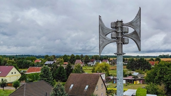 Eine Sirene ist über dem Dorf zu sehen.