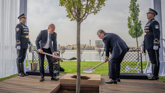 Bundeskanzler Olaf Scholz (SPD, 2.v.l.) nimmt zusammen mit Schawkat Mirsijojew, Präsident von Usbekistan, nach dem Deutsch-Ukrainischen Wirtschaftsforum an einer symbolischen Baumpflanzung teil. 