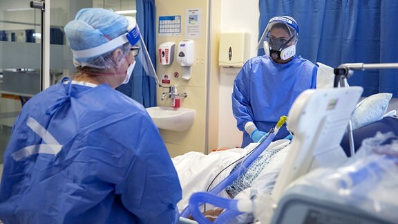 In Schutzausrüstung gekleidete Mitarbeiter des Whiston Hospitals kümmern sich um einen Patienten auf der Intensivstation.