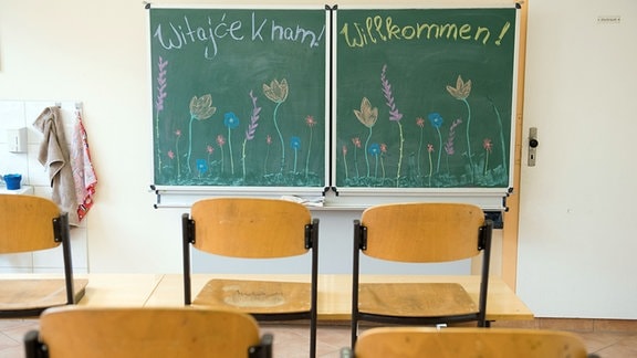 Stühle stehen in einem Klassenzimmer in der Sorbischen Oberschule vor einer Tafel mit der Aufschrift «Willkommen» in deutscher und sorbischer Sprache auf den Tischen.