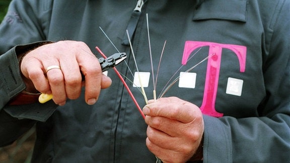 Ein Mitarbeiter der Deutschen Telekom AG kürzt ein Glasfaserkabel.