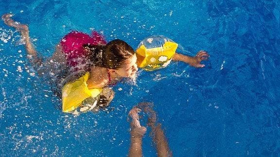 Kinder mit Schwimmflügeln in einem Schwimmbad 