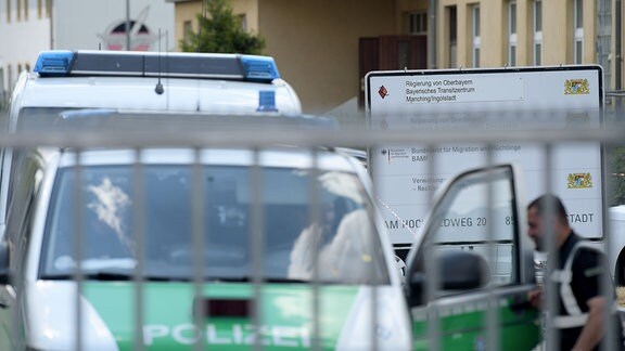 Ein Polizeifahrzeug steht im Transitzentrum für Asylsuchende vor einer Hinweistafel.