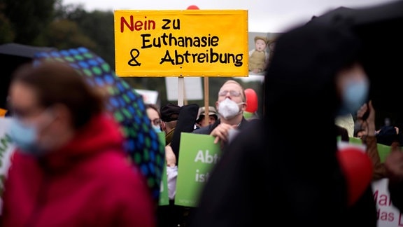 Auf der Demonstration "Marsch für das Leben" hält ein blonder Mann mit sehr kurzen Haaren ein Schild mit der Aufschrift "Nein Zu Euthanasie und Abtreibung" in die Höhe. 