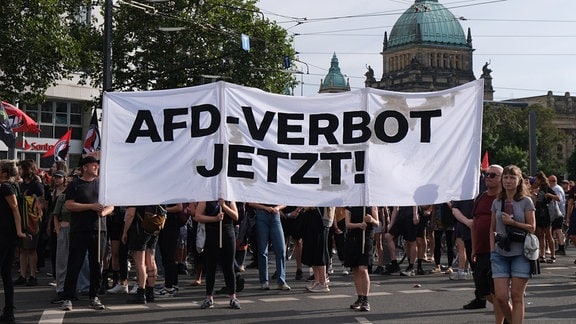 Teilnehmer einer Demonstration gegen Rechts im Vorfeld der Landtagswahl 2024 halten ein Transparent mit der Aufschrift "AfD-Verbot jetzt!". 