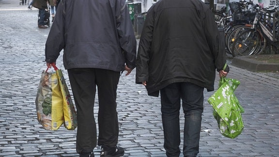 Zwei ältere Menschen tragen Einkaufstaschen.