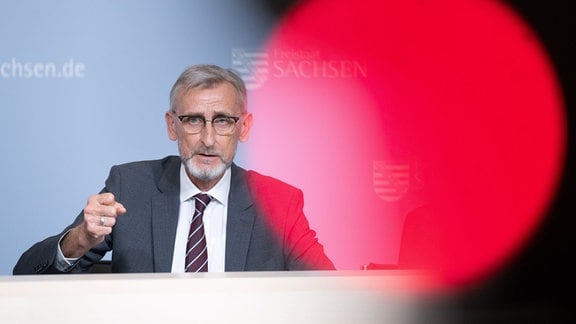 Armin Schuster (CDU), Innenminister von Sachsen, spricht auf einer Kabinetts-Pressekonferenz hinter dem roten Aufnahmelicht einer TV-Kamera.