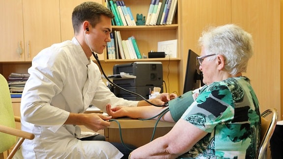 Ein Medizinstudent untersucht eine Patientin.