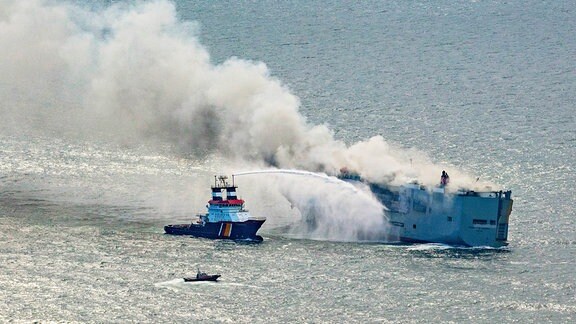 Eine Luftaufnahme zeigt den deutschen Notschlepper "Nordic" (l), der das Feuer auf einem brennenden Frachter in der Nordsee bekämpft. Wie die niederländische Küstenwache mitteilte, war auf dem Frachtschiff mit rund 3000 Autos an Bord ein Feuer ausgebrochen.