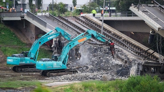 Mit zwei Baggern wird eine Brücke abgerissen.