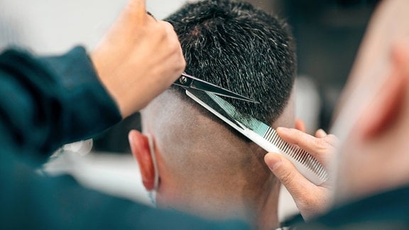 Ein Friseur schneidet einem Mann die Haare.