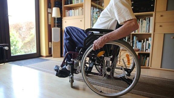 Ein älterer Mann sitzt im Rollstuhl in einer Wohnung.