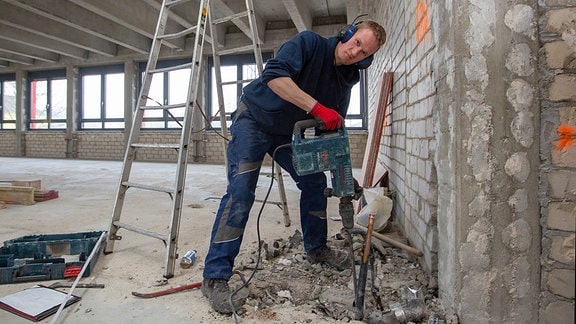 Sanierungsarbeiten, Mann mit Bohrhammer beim Abriss