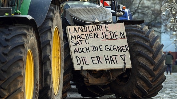 Ein Protestplakat mit der Aufschrift «Landwirte mache jeden satt, auch die Gegner die er hat!» ist bei einer Demonstration in Magdeburg an einem Traktor befestigt. 