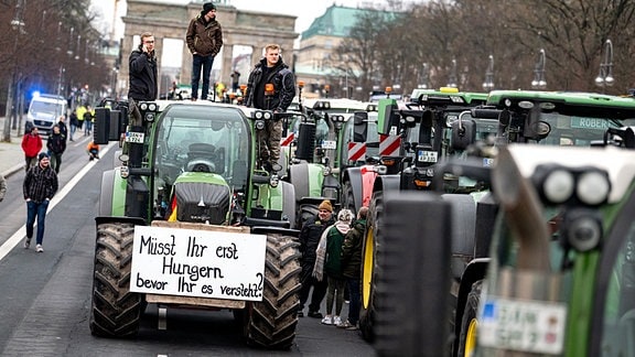 Landwirte nehmen mit Traktoren mit der Aufschrift "Müsst ihr erst Hungern bevor ihr es versteht" auf einer Demonstration des Deutschen Bauernverbandes unter dem Motto «Zu viel ist zu viel! Jetzt ist Schluss!» vor dem Brandenburger Tor teil.