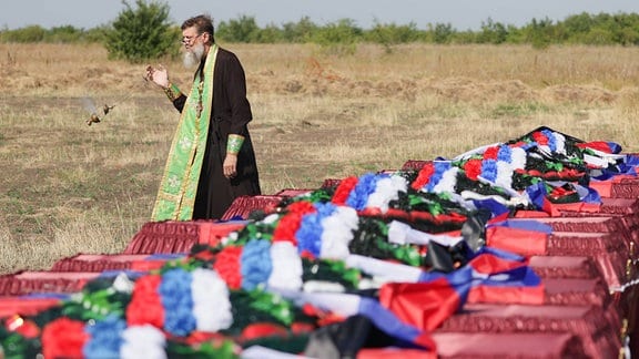 Ein Priester nimmt an einem Begräbnis von Überresten getöteter russischer Soldaten teil.