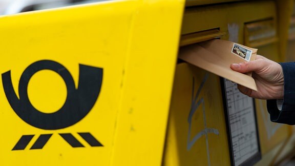Ein Brief wird in einen Postkasten gesteckt.