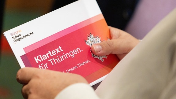 Ein Parteimitglied hält vor der Gründungsversammlung des Landesverbandes Thüringen Bündnis Sahra Wagenknecht (BSW) im Hotel «Thüringer Hof» eine Broschüre der Partei in der Hand. 