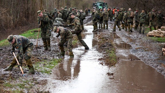 Soldatinnen und Soldaten der Bundeswehr sichern einen Deich an der Helme mit Sandsäcken