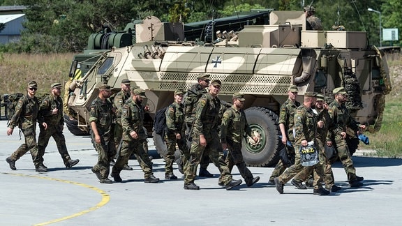 Soldaten der Bundeswehr laufen bei der Übung der Streitkräftebasis, "Brave Departure" auf dem Truppenübungsplatz Oberlausitz an einem Panzer vorbei. 